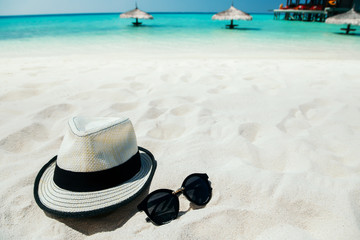 Fototapeta na wymiar Sunglasses and hat on white sand beach at tropical island