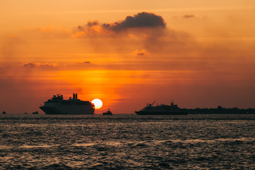 Obraz premium Cruise liner swimming on ocean at sunset