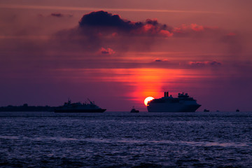 Obraz premium Cruise liner swimming on ocean at sunset