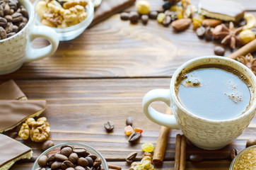 Cup of espresso black coffee on natural wooden background with healthy snacks - nuts and raisins. Copy space in the middle.