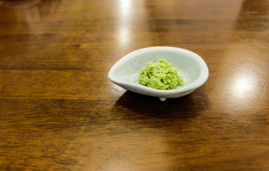 Wasabi Japanese herb in white small bowl on the wood table, close up