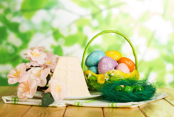 Colored Easter eggs in basket, on nest, Easter cheesecake dessert, flowers.