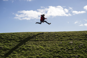 Ein Mann Hüpft auf einem Deich vor lauter Freude und Energie in die Luft