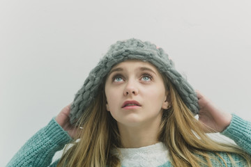 Pretty young girl with blond hair in fashionable sweater, hat