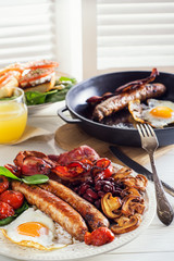 Delicious full English breakfast with  fried egg, bacon, sausage, tomatoes, beans and mushrooms. Traditional English breakfast.