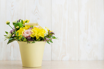 Composition of fresh flowers in a bucket on a wooden background. Copyspace