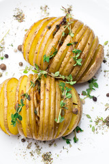 Baked potatoes with thyme on a plate close-up.