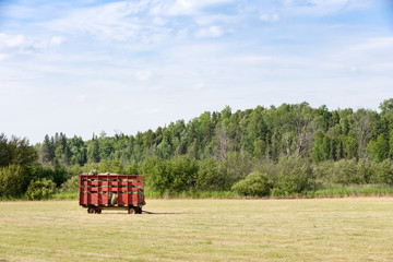 Fototapeta na wymiar Red Hay Wagon in a Farm Field
