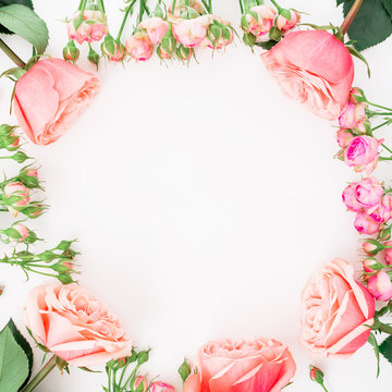 Round frame with pink roses on white background. Flat lay, top view. Floral background.