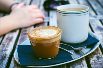  Coffee mug and cake on a wooden vintage table. Hipster concept. Woman drink a coffee. Cups of americano and macchiato. 