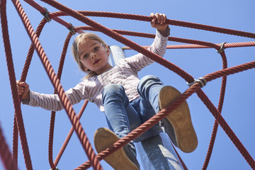 Active young child girl climbing the spider web playground activity. Children summer activities.