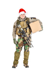 Smiling young soldier with rifle wearing Santa claus cup and holdinga cardbox