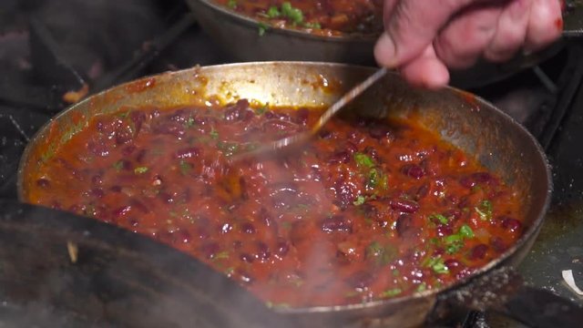 Red kidney beans frying in red sauce in pan,slow motion