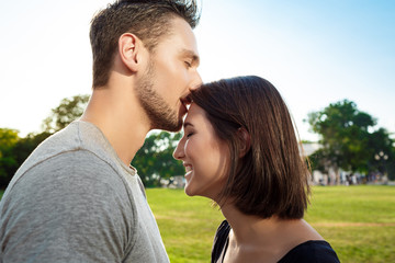 Young beautiful couple smiling, relaxing, kissing in park.