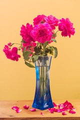 Pink roses with blue vase on wooden table top