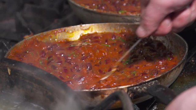 Red kidney beans frying in sauce in a pan, slow motion