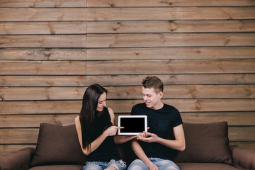 happy smiling couple sitting on sofa with tablet