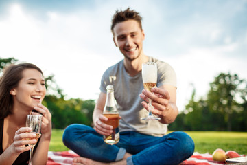 Young beautiful couple smiling, resting on picnic in park.