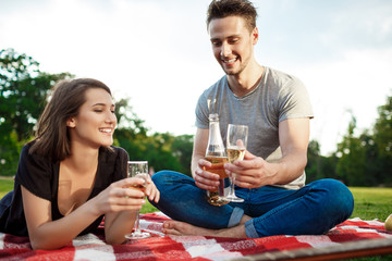 Young beautiful couple smiling, resting on picnic in park.