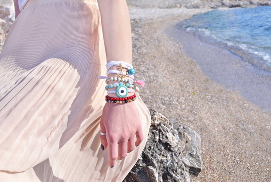model advertises bohemian greek jewelry on the beach