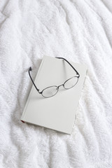 book and glasses on a bed