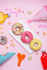 Party. Different colourful sugary round glazed donuts and bottles of drinks on pink background.