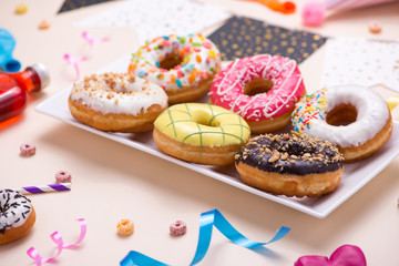 Party. Different colourful sugary round glazed donuts and bottles of drinks on light color background.
