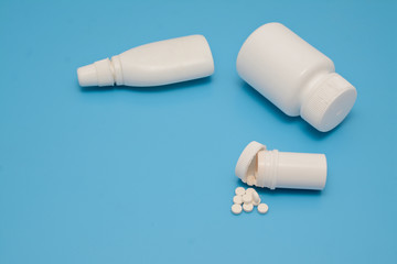 Pills and white bottles of medicine on a blue background.