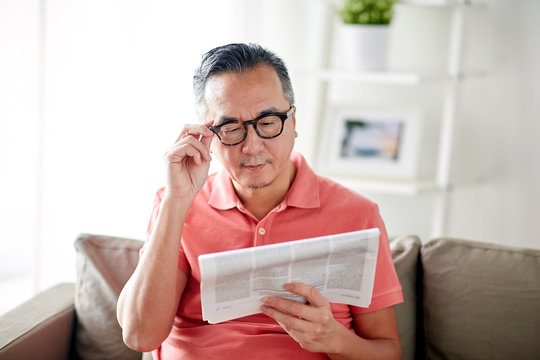 Happy Man In Glasses Reading Newspaper At Home