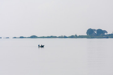 Fisher boat in Victoria Lake bay against hazy bank. Entebbe, Uganda, Eastern Africa.
