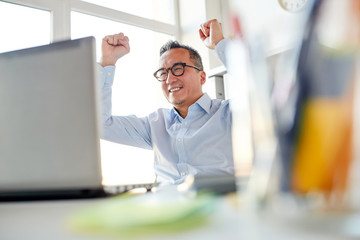 happy businessman with laptop at office