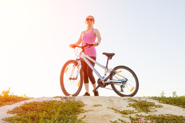 Girl with Bicycle on a background of sunrise