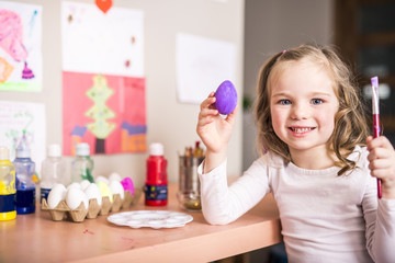 Happy easter A beautiful child girl painting Easter eggs. Happy family preparing for Easter.