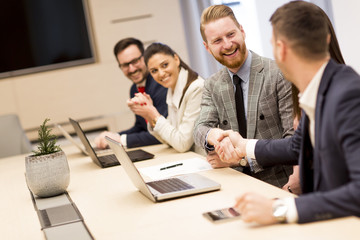 Happy smiling business team clapping hands during a meeting in office