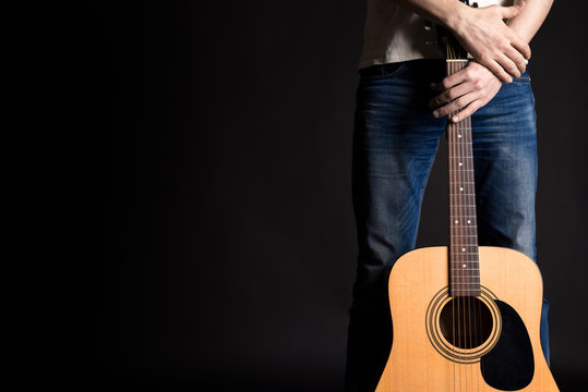 Guitarist holding two hands with an acoustic guitar on a black isolated background