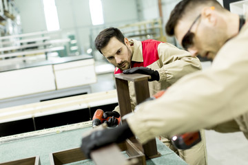 Two young men working in a factory for the production of furniture