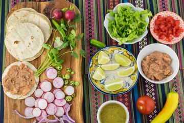 Ingredients for homemade vegetarian corn tacos with refried beans and vegetables.