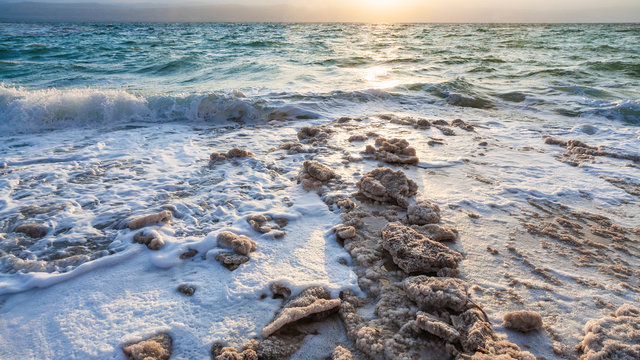 crystals of salt on shore of Dead Sea on sunset