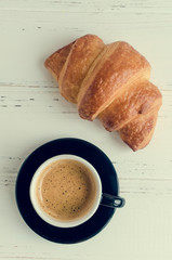 Cup of espresso coffee and fresh baked croissant