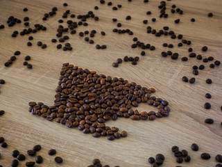 Shape of coffee cup with roasted grains over wooden background