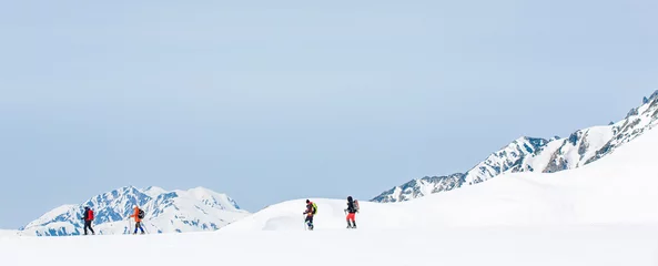 Fototapete Skiers walking on snow covered mountain ranges © aiaikawa
