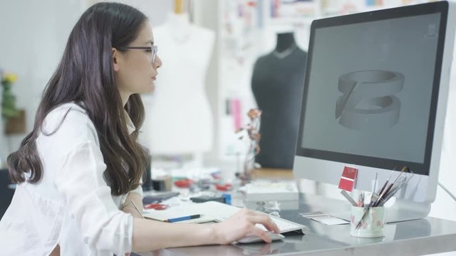 Jewelry designer working on computer checking designs with software program. 