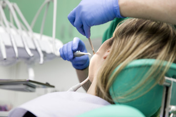 Naklejka na ściany i meble Young lady having her teeth examined by a dentist at dentist's office