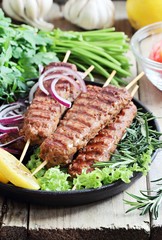  Kebab of minced beef or lamb with vegetables and herbs. Traditional meat kebab on rustic dinner table .