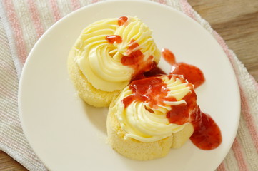 butter cake roll decorated vanilla cream dressing strawberry sauce on plate