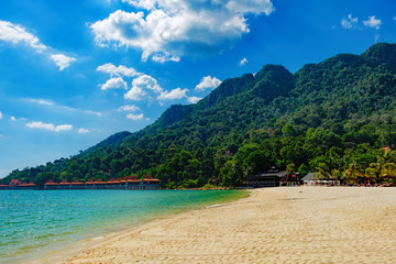 Relaxing on remote paradise beach. Tropical bungalow and luxury house on untouched sandy beach with palms trees in Langkawi Island, Malaysia.