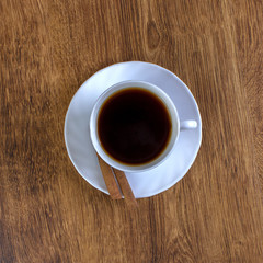A cup of coffee and cinnamon on a wooden table. View from above.