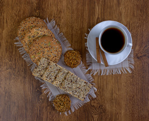Coffee drink and biscuits with cereal grains on a wooden table.
