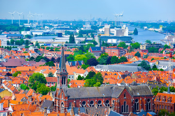 Naklejka premium Aerial view over the old town on the riverside with wind turbine and the factory as a background