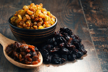 Composition with bowl of raisins on wooden table